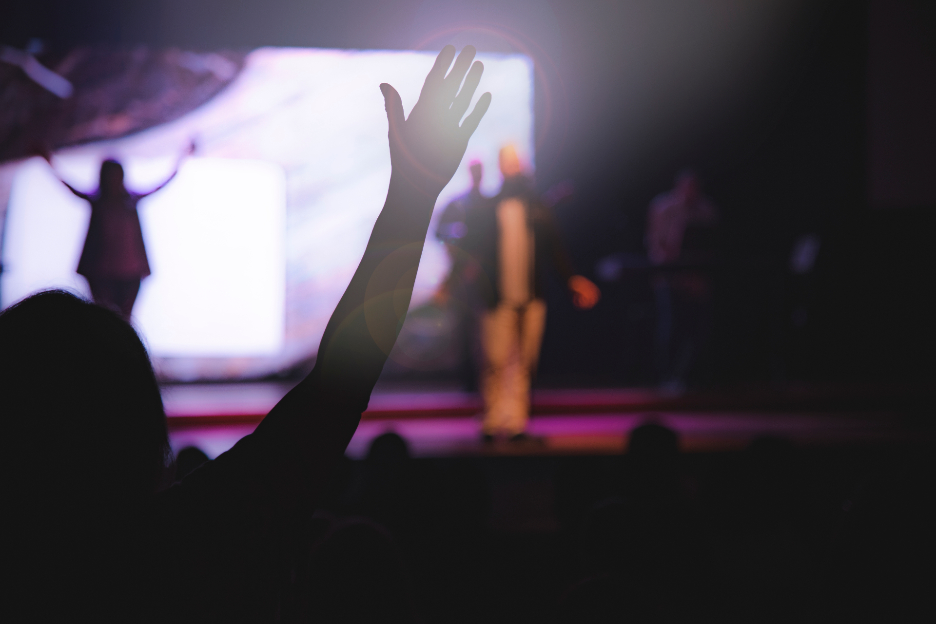 Hands raised in worship under stage lights